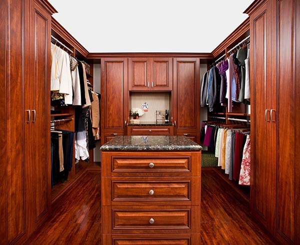 Walk in closet organization system with beautful wood cabinets and sitting area