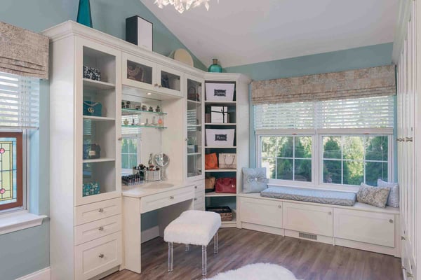 Beautiful walk-in closet with seating area, custom cabinets with mirrors and vanity